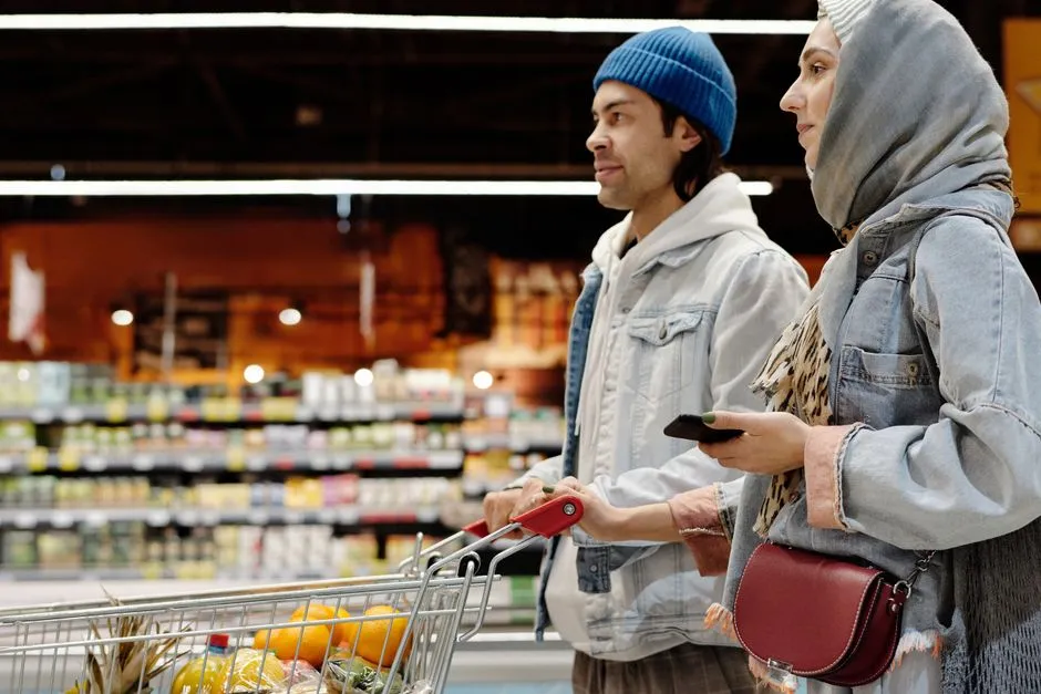 Couple pushing a shopping cart through a grocery store aisle